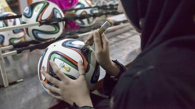An employee conducts the final check to fix any cavity in the seams of a ball inside the football factory. Sara Farid / Reuters