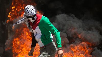 A Palestinian protester walks near burning tyres during clashes with Israeli forces during a demonstration in the village of Kfar Qaddum in the Israeli-occupied West Bank. AFP