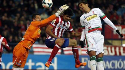 Atletico Madrid striker Diego Costa heads the ball between Granada goalkeeper Roberto Fernandez and Jose Luis Garcia for his goal on Wednesday. Sergio Perez / Reuters / March 26, 2014