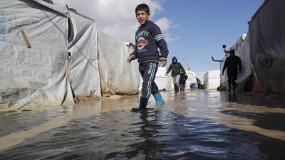 A child wades through rain and snow waters at an informal tent settlement housing Syrian refugees following winter storms in the area of Delhamiyeh, in the central Bekaa Valley on January 17, 2019. Lebanon plays host to over one million Syrian refugees who fled as neighbouring Syrian fell into civil war at the start of March 2011. / AFP / JOSEPH EID
