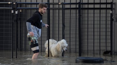 A man lets a dog out of a cage as flood waters rise in the city of Chilliwack.