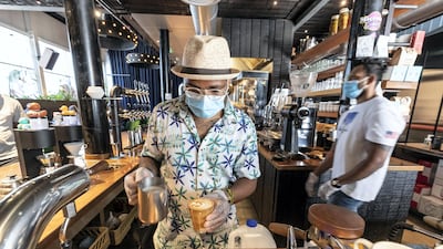 Staff at Nightjar Coffee in Dubai's Al Serkal Avenue follow sanitary procedures as they open for business. The city's hospitality sector has bounced back and a strong winter 2021 tourism season is forecast. Antonie Robertson / The National
