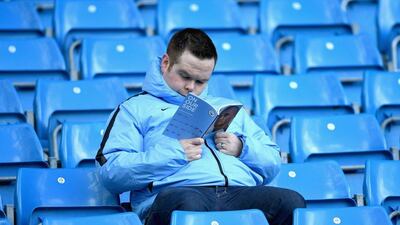 A Manchester City supporter reads the match day programme prior to the Premier League match between Manchester City and Southampton. Laurence Griffiths / Getty Images