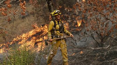 A firefighter monitors flames from an advancing wildfire Saturday, July 28, 2018, in Redding, California (AP)
