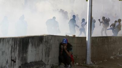 An anti-government student protects herself during clashes with the National Guard in Caracas on February 16, 2014. Supporters and opponents of Venezuela’s leftist government have been staging rival rallies amid spiralling discontent at the country’s stubborn inflation and shortage of basic goods. Juan Barreto / AFP photo