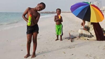 Children playing on the beach in Ajman while their mother rests under the umbrella nearby. Jeff Topping/The National