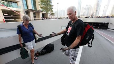 Jim Bishop and Jane Bishop come out with their belongings from Tamweel Tower in Jumeirah Lakes Towers.