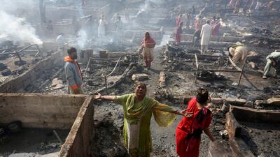 A woman griefs while she and others collect their belongings in Karachi, Pakistan, Saturday, Nov. 20, 2021, following a fire that gutted hut homes. Scores of huts were burnt to ashes as the fire erupted making dozens of families homeless in a slum of Karachi, local media reported. (AP Photo / Fareed Khan)