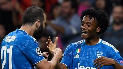 Juventus' Colombian midfielder Juan Cuadrado is congratulated by teammate Gonzalo Higuain after scoring the opening goal against Atletico Madrid at The Wanda Metropolitano Stadium in Madrid. The Champions League Group D match ended 2-2. AFP