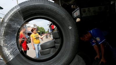 A Venezuelan woman looks for tyres at a stall in Puerto Santander, Colombia. The Venezuelan collapse has left shortages of everything in the country. Carlos Garcia Rawlins/Reuters