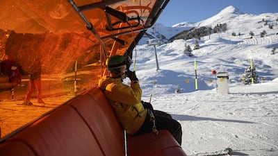 A skier adjusts his protective face mask on a chairlift at the Kleine Scheidegg ski resort in Grindelwald, Switzerland. Bloomberg