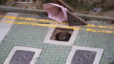 A broken umbrella lies next to the manholes at the Hong Kong Polytechnic University which protesters has tried to use it to escape. AP Photo