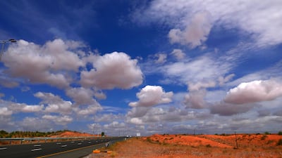 Clouds, mountains and the red sand of the Northern Emirates.