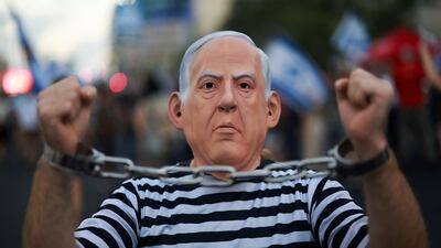 A masked man protests against Benjamin Netanyahu's government in Tel Aviv. Britain's Labour government has to decide on whether to continue the Conservative challenge against the ICC’s arrest ruling for the Israeli Prime Minister. Reuters