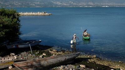 A fisherman carries a bucket from his boat to the shore in Port-au-Prince, Haiti, on July 19. The country of more than 11 million people are still reeling from the July 7 killing of President Jovenel Moise. AP