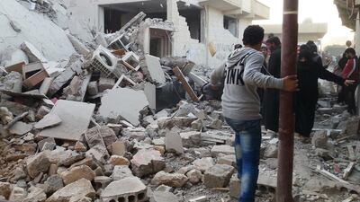 People walk past a building that was reportedly targeted by the US-led coalition, in the ISIL controlled Syrian city of Raqqa in 2014. An airstrike 21 June 2016 killed 25 people. AFP PHOTO/RMC/STR / AFP PHOTO / Raqa Media Center / STR