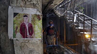 A municipal worker passes by a poster of a bomb victim during the cleaning process at the site of a deadly Islamic State group-claimed mall bombing in the Karradah neighborhood of central Baghdad, Iraq. Khalid Mohammed / AP Photo