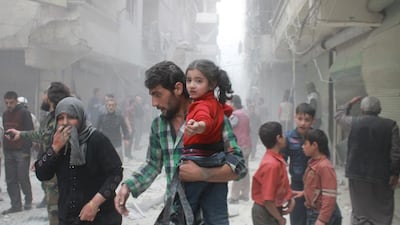 A Syrian man carrying a child makes his way amid rubble following reported air strikes by government forces in Aleppo. Baraa Al Halabi / AFP Photo