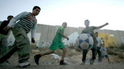 Palestinian Children play football beside the separation wall that separate Jerusalem from West Bank in Qalandia refugee camp.