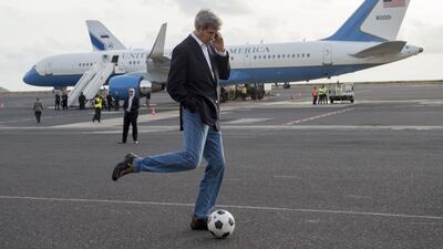US Secretary of State John Kerry kicks around a football ball while talking on his cellphone during an airplane refuelling stop at Sal Island, Cape Verde, en route to Washington, DC. Saul Loeb / AFP