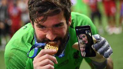 Alisson takes a playful bite out of his medal in Madrid. Getty