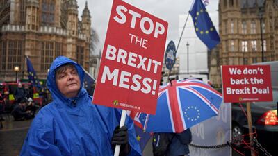 Brexit protesters shelter from a rain shower outside the houses of parliament in London. EPA