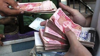 Currency dealers count rupees. A widening current account deficit and dwindling reserves could cause Pakistan to default. Muhammad Sajjad / AP Photo