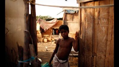 A boy stands at the door of his family's hut.