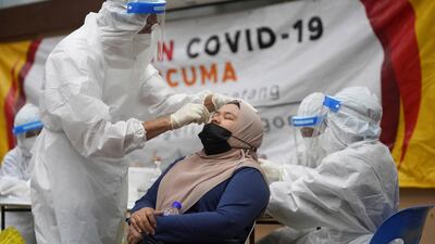 A medical worker collects a swab sample from a woman at a Covid-19 testing centre in Ulu Klang, on the outskirts of Kuala Lumpur, Malaysia. AP
