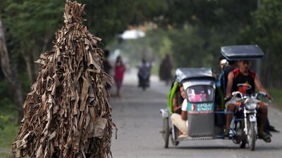 A resident, with his whole body covered in mud and donning dried Banana leaves, collects candles. Bullit Marquez / AP Photo