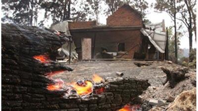 A tree burns close to a burnt out house at Kinglake, north of Melbourne, on Feb 8 2009.