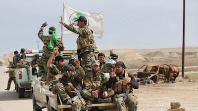 Members of the Iraqi paramilitary Popular Mobilisation units flash the 'V' for victory sign after regaining control of the village of Albu Ajil, near Tikrit, on March 9, 2015.