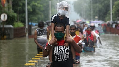 A man carries a child through a waterlogged road after heavy rainfall in Mumbai, India. REUTERS