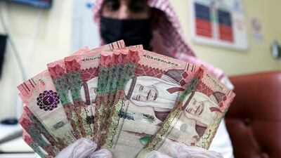 A Saudi money exchanger wears a protective face mask and gloves as he counts riyals in Riyadh, Saudi Arabia. Reuters