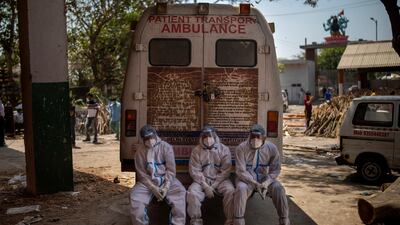 Exhausted workers, who bring bodies for cremation, on the rear step of an ambulance inside a crematorium, in New Delhi, India, April 24. AP