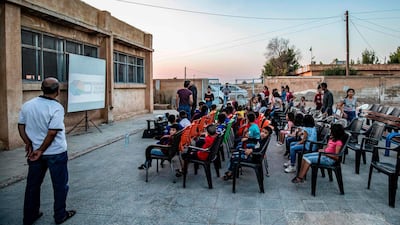 Children attend a film screening as part of the mobile cinema "Komina Film" at a school yard in Shaghir Bazar, in northeastern Syria's Hasakeh province. All photos by AFP