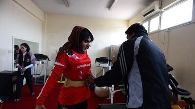Afghan weightlifting coach Shahpoor supervises a young woman during a training session.