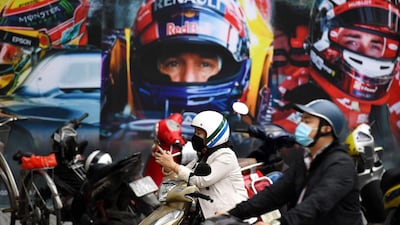 A woman wearing a facemask checks her smartphone in front of a poster outside the Formula One Vietnam Grand Prix merchandise store in Hanoi on March 2, 2020 amid concerns of the Covid-19 coronavirus outbreak. AFP