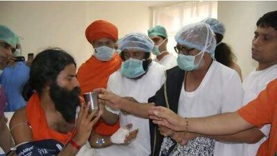 Baba Ramdev, left, is offered a glass of juice by the Hindu scholar Morari Bapu, second right, and the Indian spiritual leader Sri Sri Ravishankar, centre, as he breaks his fast at a hospital in Haridwar, India, yesterday. Patanjali Yogpeeth / AP Photo