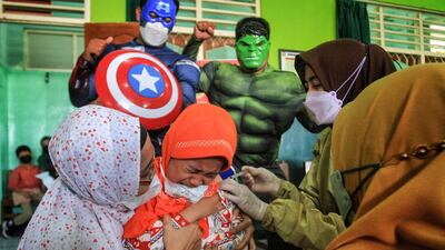 Medical staff dressed in superhero costumes accompany children aged 6 to 11 as they receive a vaccine at a school in Yogyakarta, Indonesia. AFP
