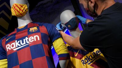 An employee places the mask with the FC Barcelona's logo on a mannequin at the FC Barcelona store. AFP