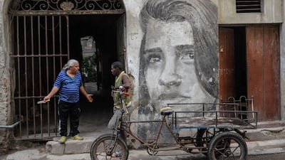 Cubans stand by a mural.