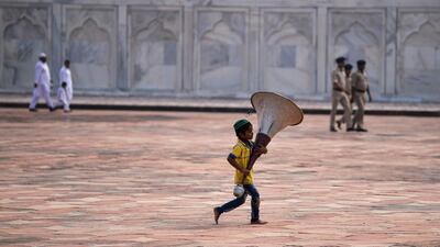 An Indian Muslim boy runs as he holds a speaker during the Eid Al Adha festival at the mosque inside the Taj Mahal in Agra. AFP