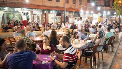 People play cards and smoke shisha at a cafe in Tripoli old souk