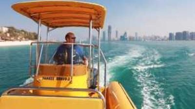 Michael Phillips, the chief executive of the Yellow Boats touring company, pilots a speed boat equipped for groups of tourists along the Corniche of Abu Dhabi.
