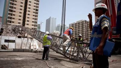 Construction workers work away to clean up remains of a crane that collapsed earlier that morning on Tuesday, July 12, 2011, during the morning rush hour in downtown Abu Dhabi. No one was hurt and only road blocks and the crane itself suffered damages.