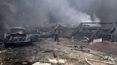 A Syrian security officer walks past burning cars at the scene of a car bomb explosion which rocked central Damascus.