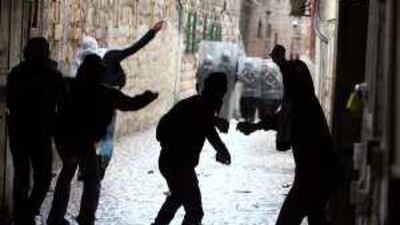 Palestinian youths throw stones at Israeli soldiers and policemen during clashes near Al Aqsa in Jerusalem yesterday.