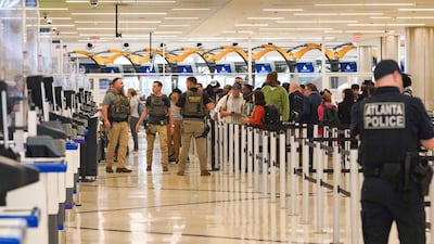 Airport officers stand nearby as ICE agents check IDs and direct travellers at the TSA security checkpoint at Atlanta Hartsfield-Jackson International Airport. AFP