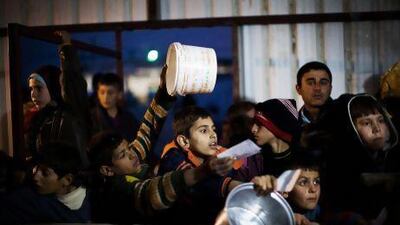 Syrian children wait in line for food to be distributed at a refugee camp near the Turkish border, in Azzaz, Syria on December 9.